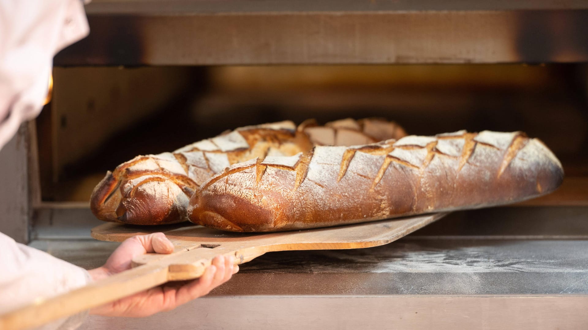 Ein Bäcker schiebt Brote in den Ofen (Symbolbild): In Dortmund macht eine beliebte Bäckerei zu. Ein Bäcker schiebt Brote in den Ofen (Symbolbild): In Dortmund macht eine beliebte Bäckerei zu.