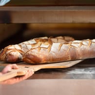 Ein Bäcker schiebt Brote in den Ofen (Symbolbild): In Dortmund macht eine beliebte Bäckerei zu.