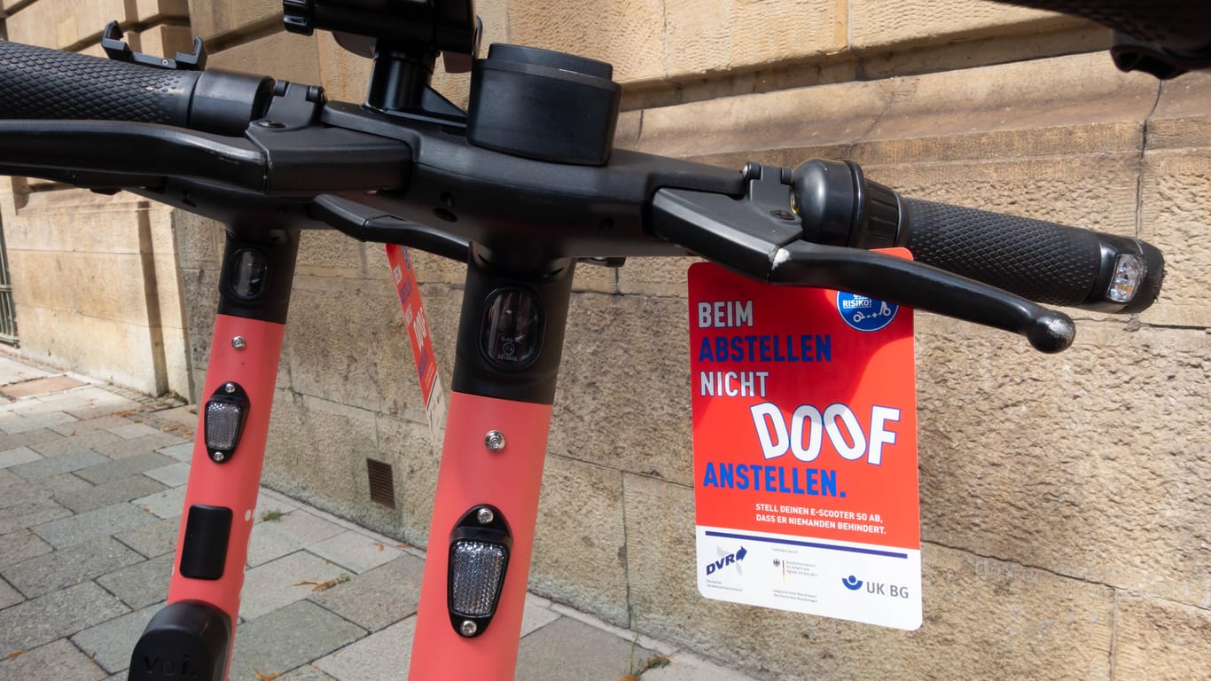 E-Scooter stehen vor einem Schild, auf dem "Beim Abstellen nicht doof anstellen" steht (Archivbild): In München ärgern sich viele über falsch abgestellte Scooter.