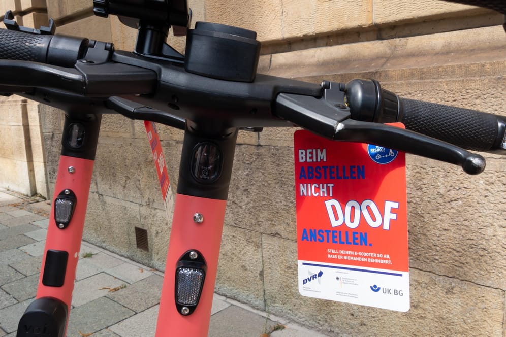 E-Scooter stehen vor einem Schild, auf dem "Beim Abstellen nicht doof anstellen" steht (Archivbild): In München ärgern sich viele über falsch abgestellte Scooter.
