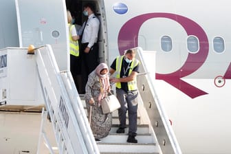 Ein Flughafenmitarbeiter hilft einer geflüchteten Frau aus Afghanistan aus dem Flugzeug: Die EU will 100 Millionen Euro zusätzliche Hilfe geben.