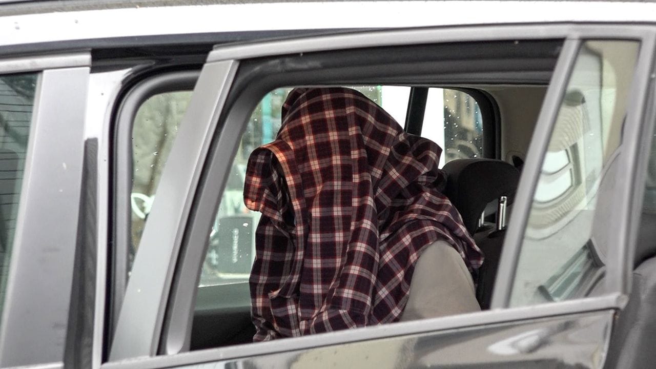 Mit Hemd über dem Kopf: Nach seiner Festnahme sitzt ein Mann in einem Auto der Einsatzkräfte. Mit Hemd über dem Kopf: Nach seiner Festnahme sitzt ein Mann in einem Auto der Einsatzkräfte.