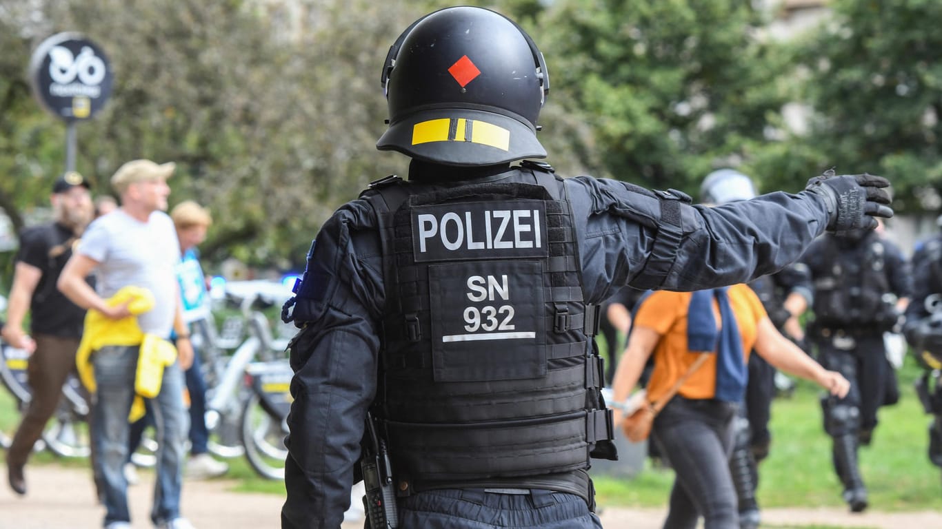 Ein Polizist in Schutzausrüstung begleitet einen "Querdenker"-Protest in Berlin (Symbolbild): Im Wedding sollen sich sogenannte Querdenker zu einer Straßenblockade zusammengetan haben.