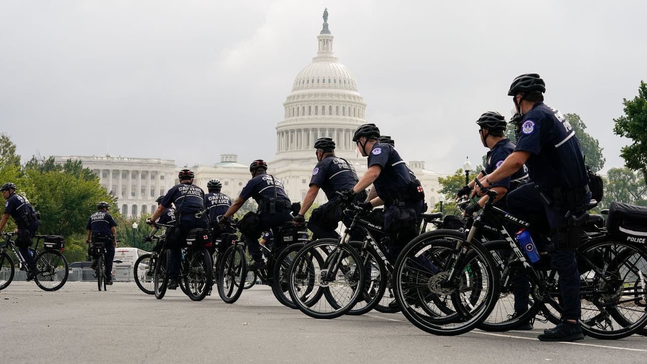 Polizisten auf Fahrrädern beobachten eine Kundgebung in der Nähe des Kapitols.