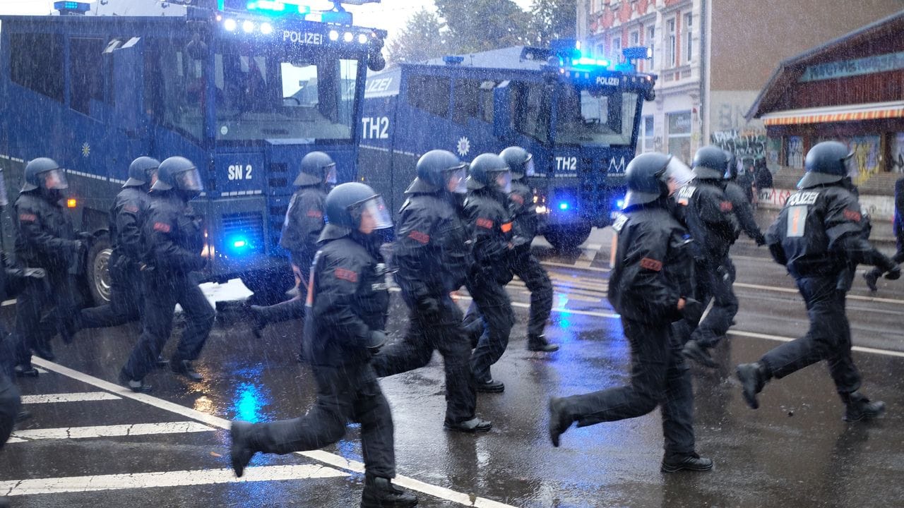 Polizisten laufen über eine Kreuzung im Leipziger Stadtteil Connewitz.
