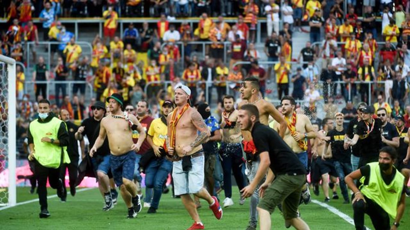 Fans von RC Lens und OSC Lille stürmen auf das Spielfeld des Stade Bollaert-Delelis.
