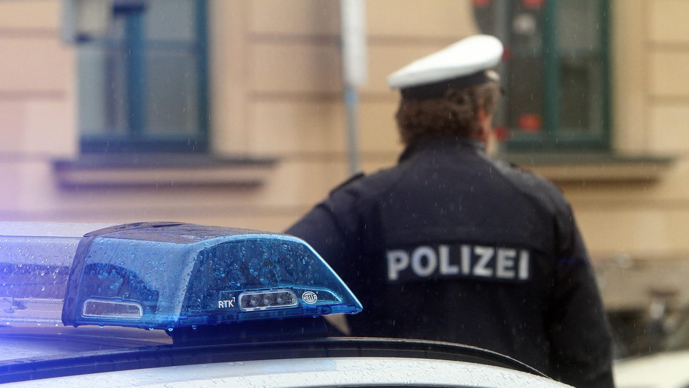 Ein Polizist vor einem Einsatzwagen (Symbolbild): In Leverkusen hat die Polizei die Wohnung eines Verdächtigen durchsucht.
