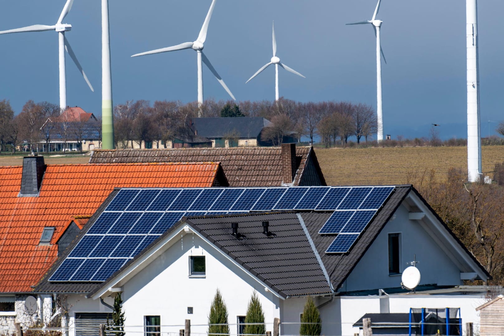 Windkraftanlagen und Wohnhäuser mit Solaranlagen (Symbolbild): Viele Parteien wollen erneuerbare Energien ausbauen.