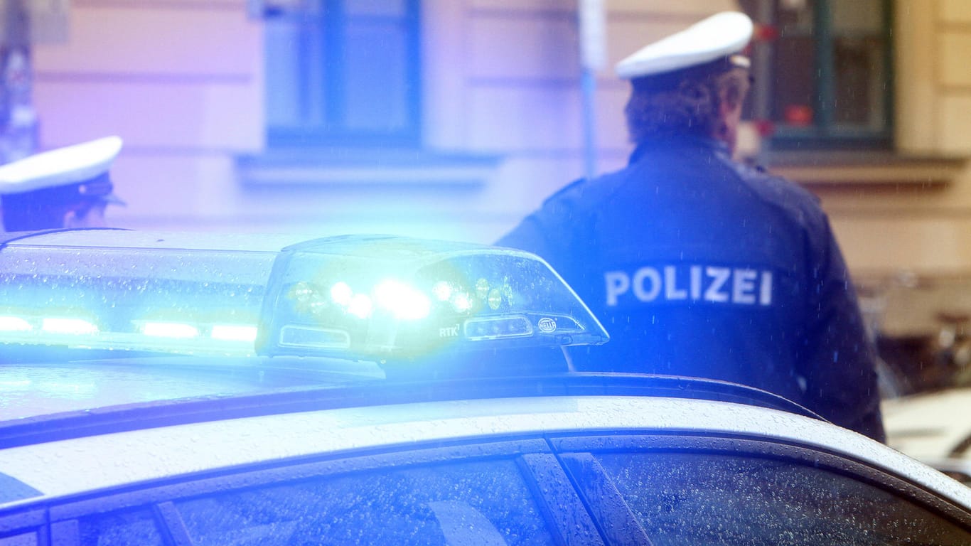 Ein Polizist steht vor einem Einsatzwagen (Symbolbild): In Hannover ist ein 19-Jähriger mit einem spitzen Gegenstand verletzt worden.
