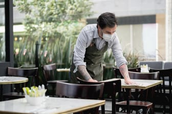 Kellner mit Maske im Restaurant: Der Dienstleistungssektor erholt sich aktuell wieder, dennoch dürfte die Wirtschaft laut Ifo-Institut deutlich langsamer wachsen als erwartet.