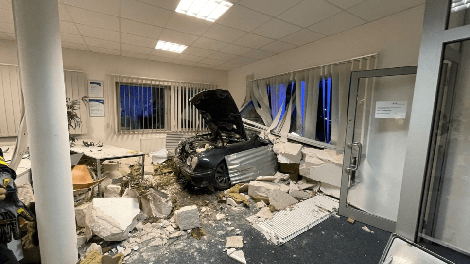 Ein Wagen steht mit der Motorhaube in einem Büro: Der Unfallfahrer wurde nur leicht verletzt. Ein Wagen steht mit der Motorhaube in einem Büro: Der Unfallfahrer wurde nur leicht verletzt.