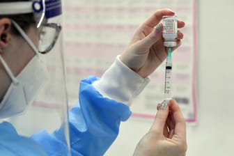 Eine Pharmazeutin zieht eine Spritze mit Impfstoff auf (Symbolbild): Ökonomen gehen von hohen Kosten für die Allgemeinheit durch Ungeimpfte aus.