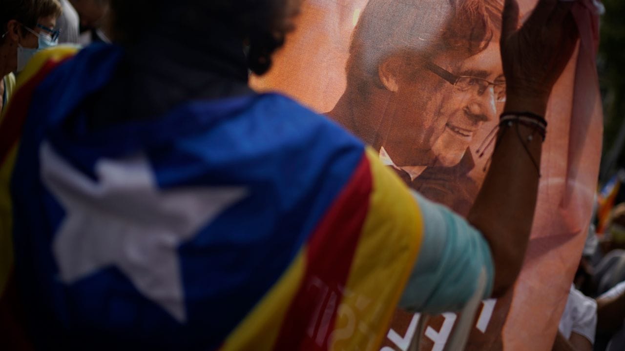 Ein Mann hält ein bedrucktes Tuch mit dem Bild des ehemaligen katalanischen Regierungschefs Puigdemont während eines Protests vor dem italienischen Konsulat in Barcelona. Ein Mann hält ein bedrucktes Tuch mit dem Bild des ehemaligen katalanischen Regierungschefs Puigdemont während eines Protests vor dem italienischen Konsulat in Barcelona.