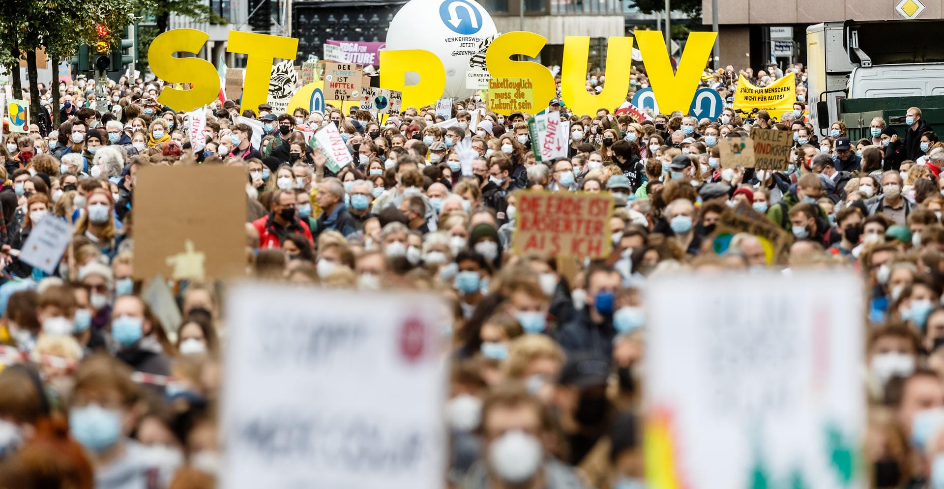 In Hamburg halten Aktivisten auf der Klima-Demo Buchstaben, die die Worte "STOP SUV" bilden, in die Höhe. Sie fordern sozial gerechte und effektive Maßnahmen, um den globalen Temperaturanstieg auf 1,5 Grad Celsius zu begrenzen.