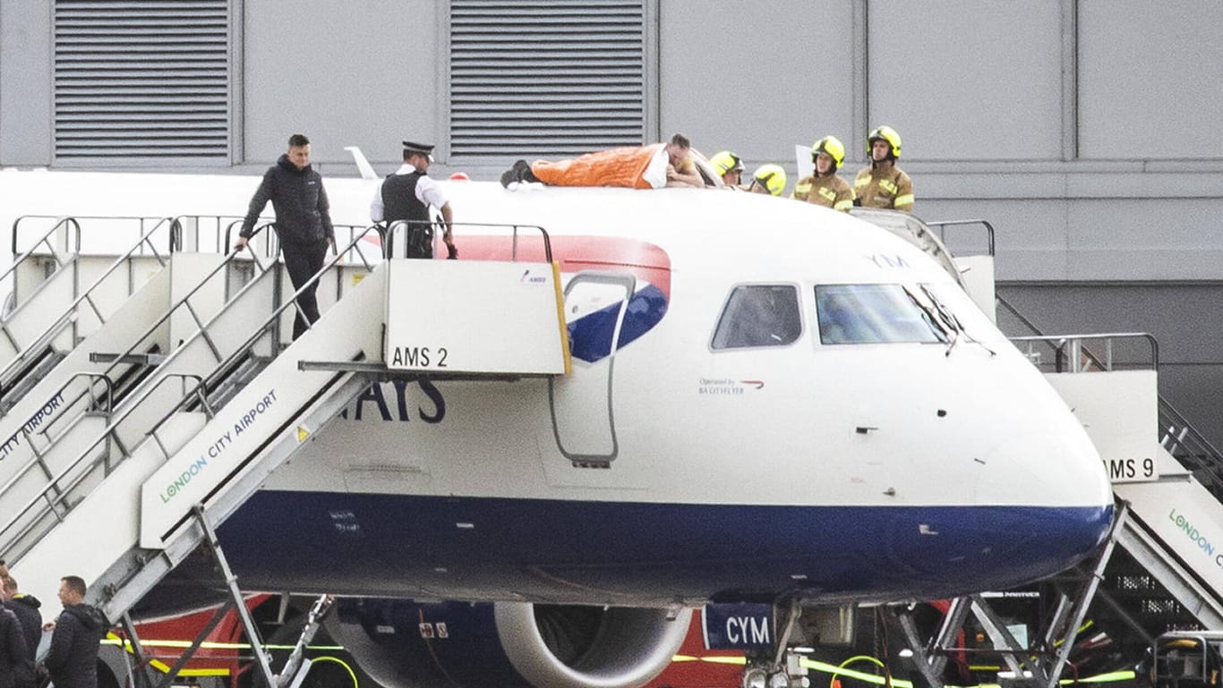 Skurrile Aktion: James Brown (in Orange) kletterte auf eine British-Airways-Maschine und klebte seine Hand an der Flugzeughülle fest.