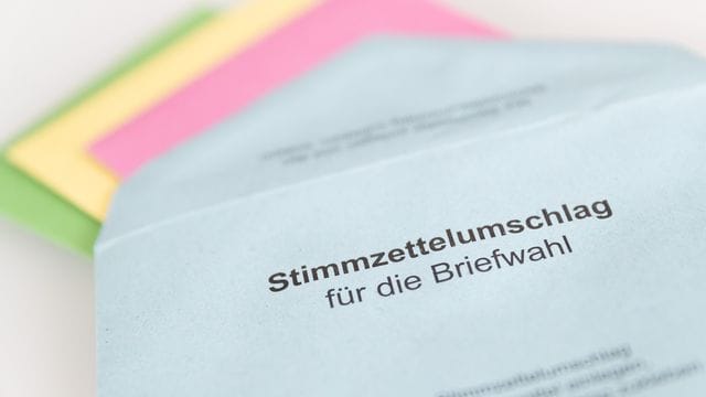 Verschiedene Stimmzettel stecken in einem Umschlag zur Briefwahl