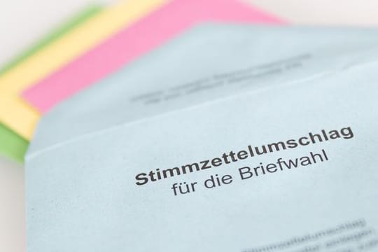 Verschiedene Stimmzettel stecken in einem Umschlag zur Briefwahl