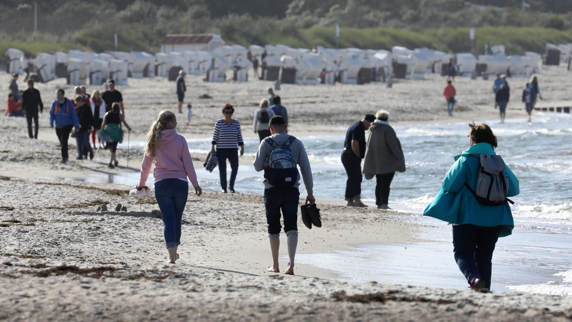 Spaziergänger genießen die Sonne am Strand von Warnemünde: An der Küste kann es auch am Samstag wieder sonnig werden. Spaziergänger genießen die Sonne am Strand von Warnemünde: An der Küste kann es auch am Samstag wieder sonnig werden.