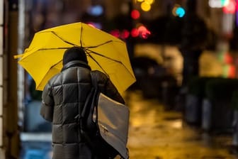 Ein Passant geht bei Regen durch die Stadt