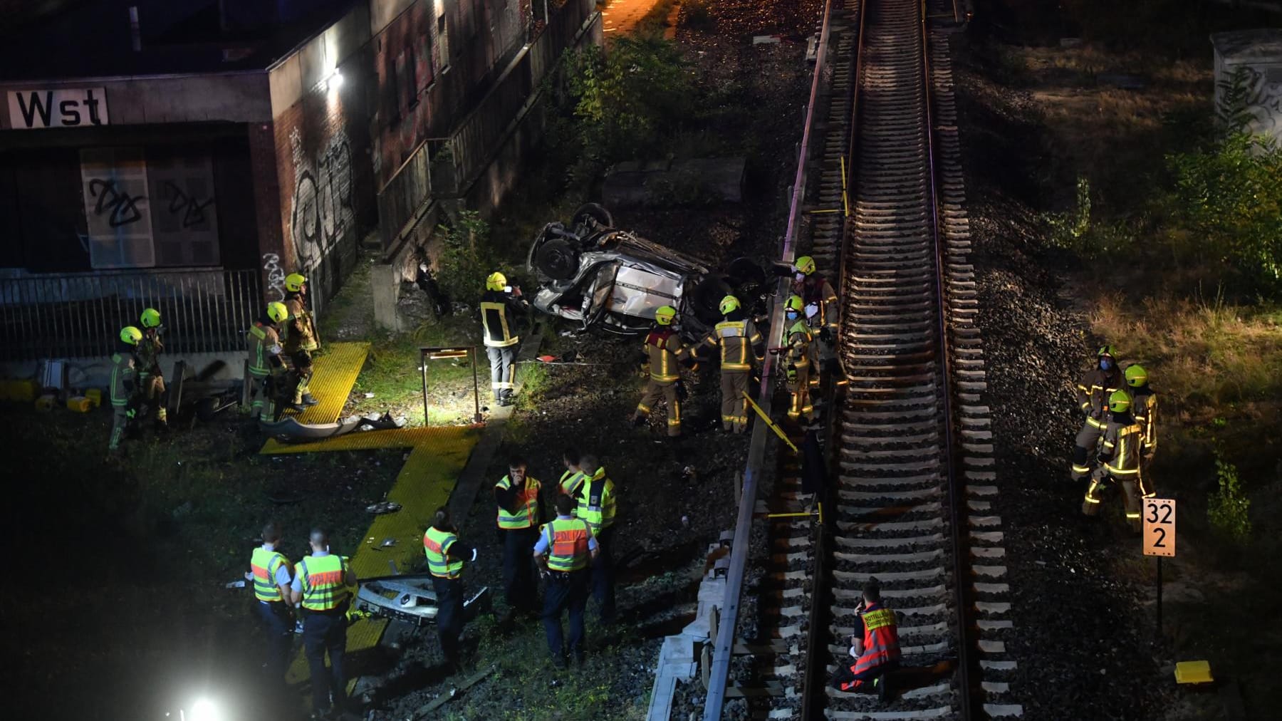 Der verunfallte Wagen liegt neben den Gleisen am S-Bahnhof Westend: In Berlin ist ein Auto von einer Autobahnbrücke gestürzt.