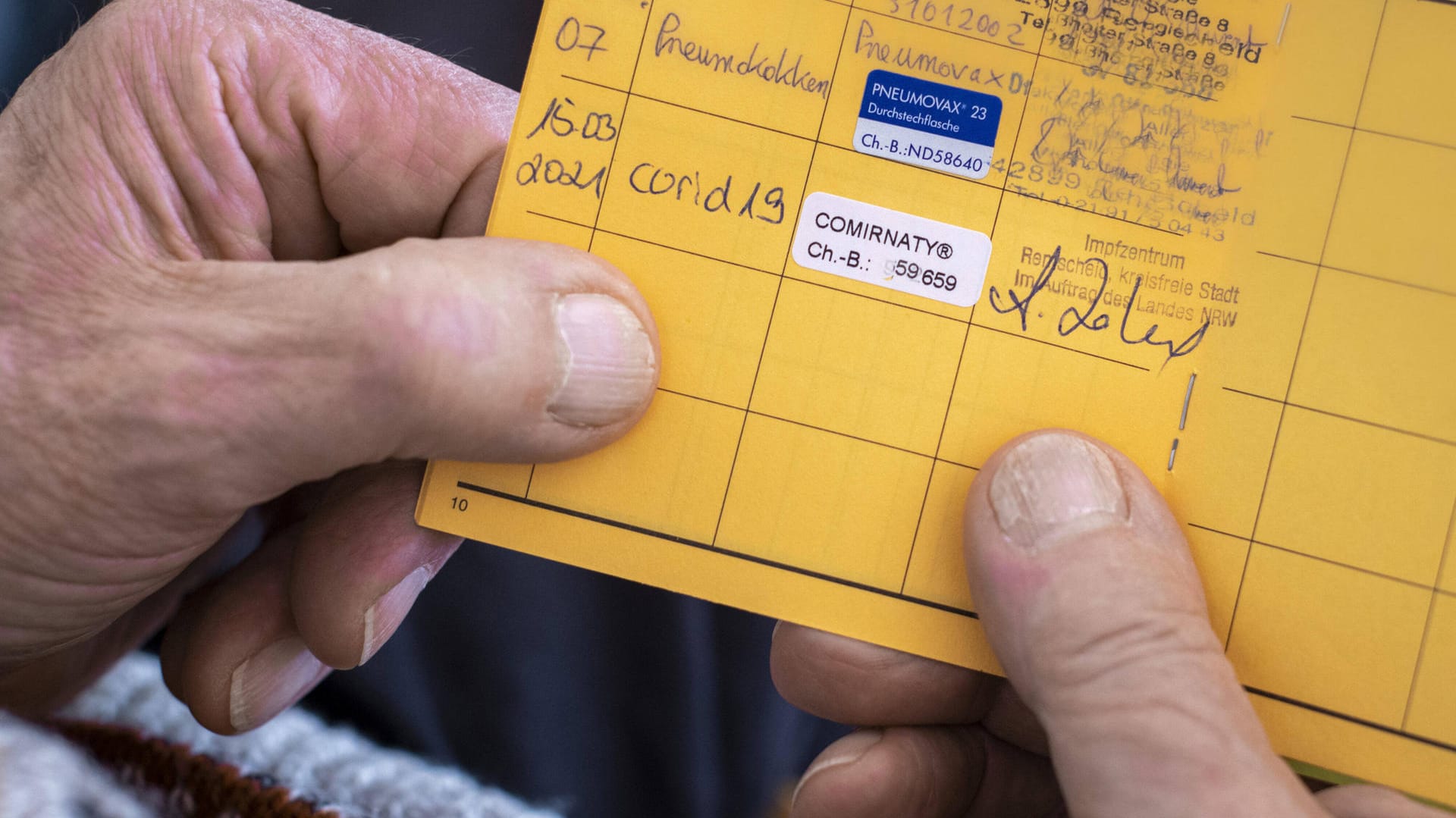 Ein Mann hält seinen Impfpass in den Händen (Symbolbild): Die Polizei Köln hat eine Ermittlungsgruppe zu gefälschten Impfpässen eingerichtet.