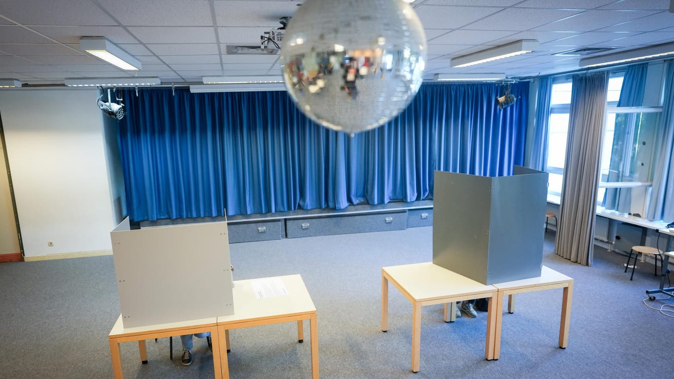 Unter einer Diskokugel sitzen Wähler in der Wahlkabine für die Bundestagswahl und die Wahl des Abgeordnetenhauses: In Berlin wurden Stimmzettel zwischen den Bezirken vertauscht.