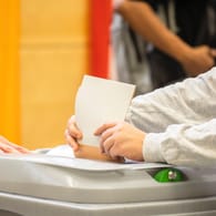 Eine Person wirft einen Wahlzettel in eine Wahlurne in Berlin (Symbolbild): In einem Wahllokal in Pankow mussten Wähler nach Hause geschickt werden.