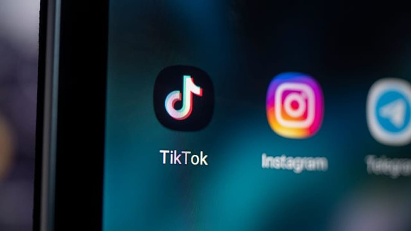 Das Logo der App TikTok (l) auf dem Bildschirm eines Smartphones.