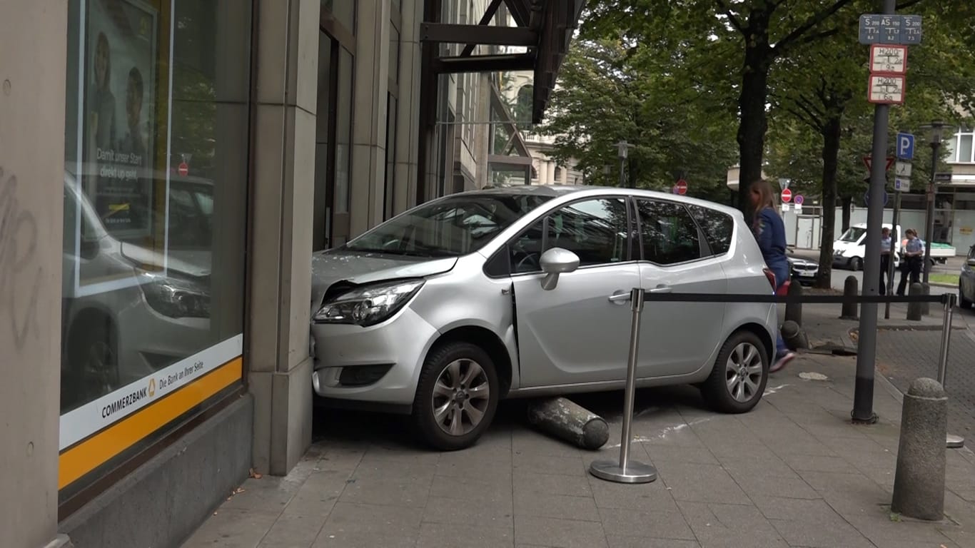 Ein Auto steht auf dem Gehweg, nachdem eine Seniorin mit dem Wagen durch die Glastür einer Bankfiliale gekracht ist: Die Fahrerin wurde leicht verletzt.