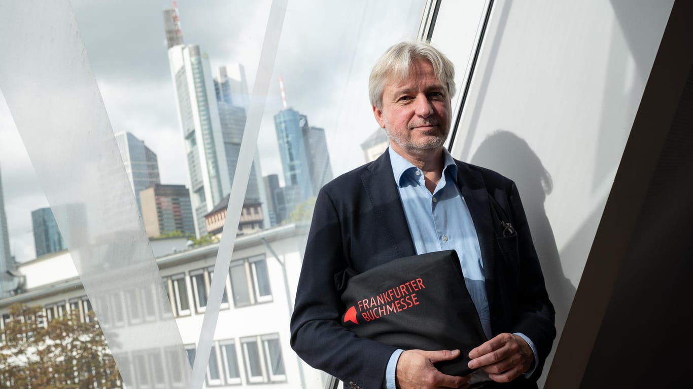 Jürgen Boos, Direktor der Frankfurter Buchmesse, vor einem Fenster mit der Frankfurter Skyline: In diesem Jahr wird die Buchmesse eine hybride Veranstaltung.