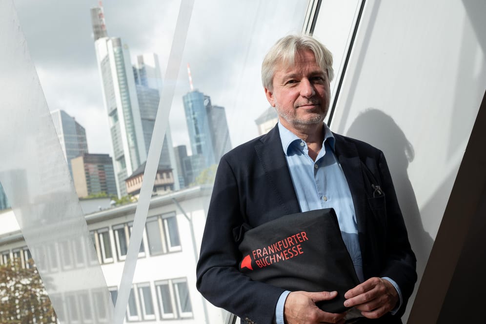 Jürgen Boos, Direktor der Frankfurter Buchmesse, vor einem Fenster mit der Frankfurter Skyline: In diesem Jahr wird die Buchmesse eine hybride Veranstaltung.