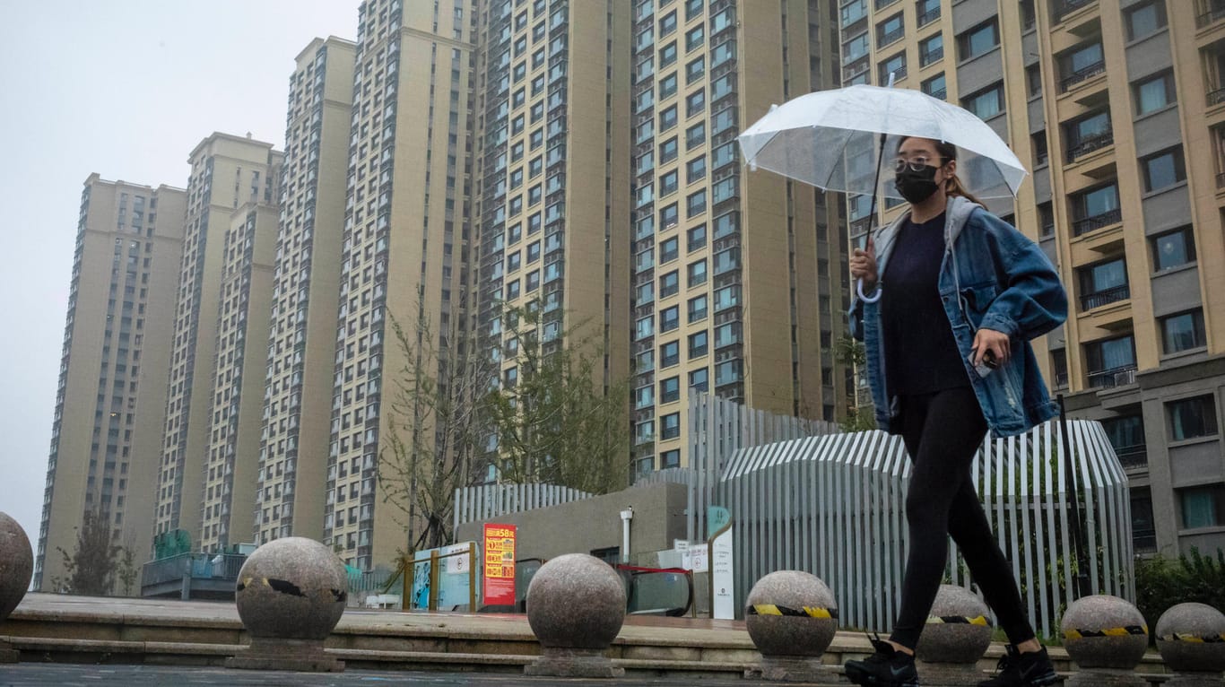 Eine Passantin geht an einem Gebäudekomplex von Evergrande in Peking vorbei: Die Krise des Immobilienkonzerns wirkt sich bereits auf die Wachstumsprognosen für China aus.