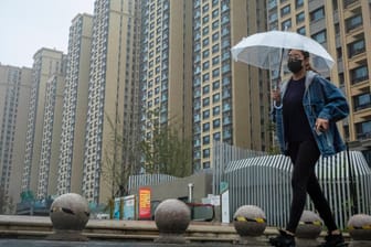 Eine Passantin geht an einem Gebäudekomplex von Evergrande in Peking vorbei: Die Krise des Immobilienkonzerns wirkt sich bereits auf die Wachstumsprognosen für China aus.