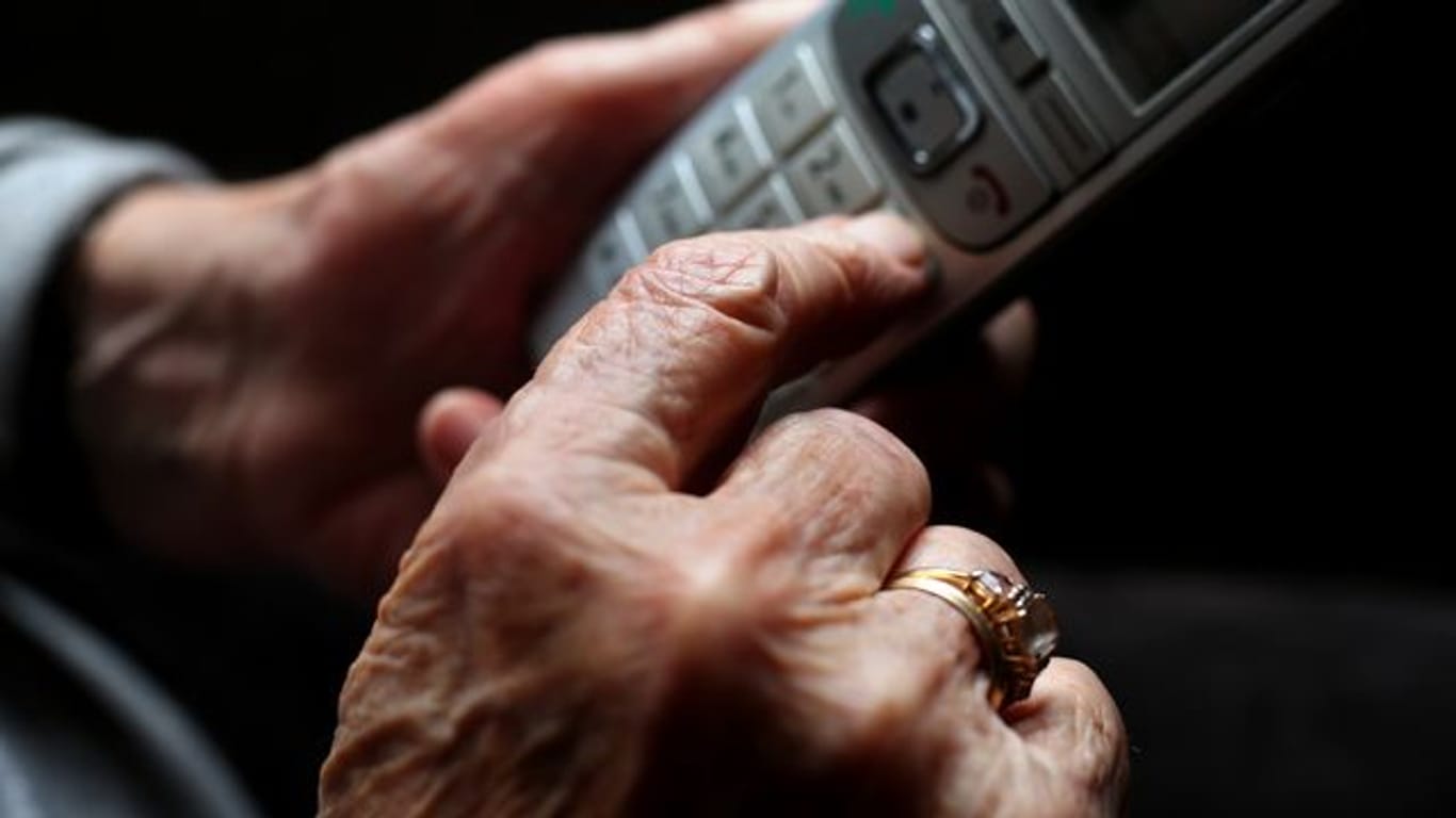 Eine ältere Frau tippt auf einem Festnetztelefon (Symbolbild): Die Anrufe bei Telefonseelsorgen haben durch die Pandemie zugenommen.