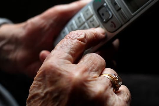 Eine ältere Frau tippt auf einem Festnetztelefon (Symbolbild): Die Anrufe bei Telefonseelsorgen haben durch die Pandemie zugenommen.