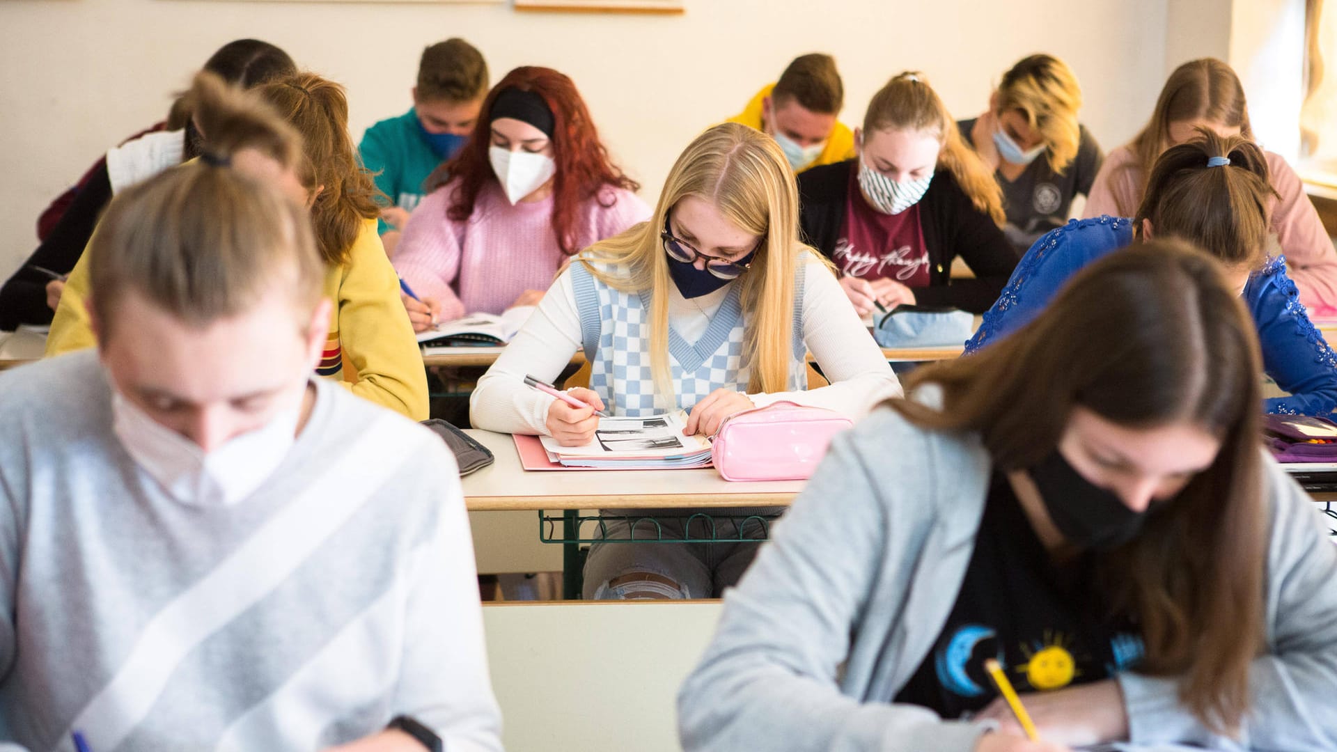 Schülerinnen und Schüler sitzen mit Maske im Unterricht (Archivbild): Die Maskenpflicht am Platz soll in Schulen in Bayern fallen.