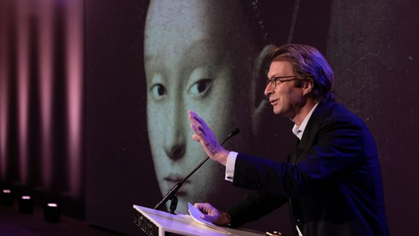Taco Dibbits, Generaldirektor des Rijksmuseums, spricht über die Ausstellung "Remember Me" (dt: Vergiss mich nicht), während das Porträt einer jungen Frau von Petrus Christus auf die Leinwand projiziert wird.