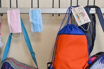 Masken und Taschen hängen in einer Grundschule an Kleiderhaken