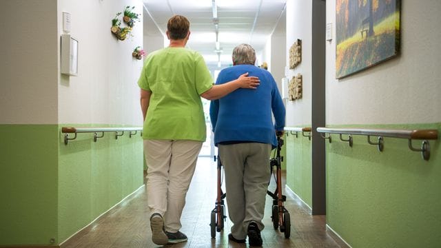 Eine Pflegekraft geht mit einer Bewohnerin eines Seniorenheims Eine Pflegekraft geht mit einer Bewohnerin eines Seniorenheims
