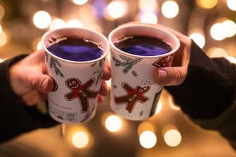 Zwei Besucherinnen eines Weihnachtsmarktes stoßen mit Glühwein an (Symbolbild): In Baden-Württemberg sollen wieder Weihnachtsmärkte möglich sein.