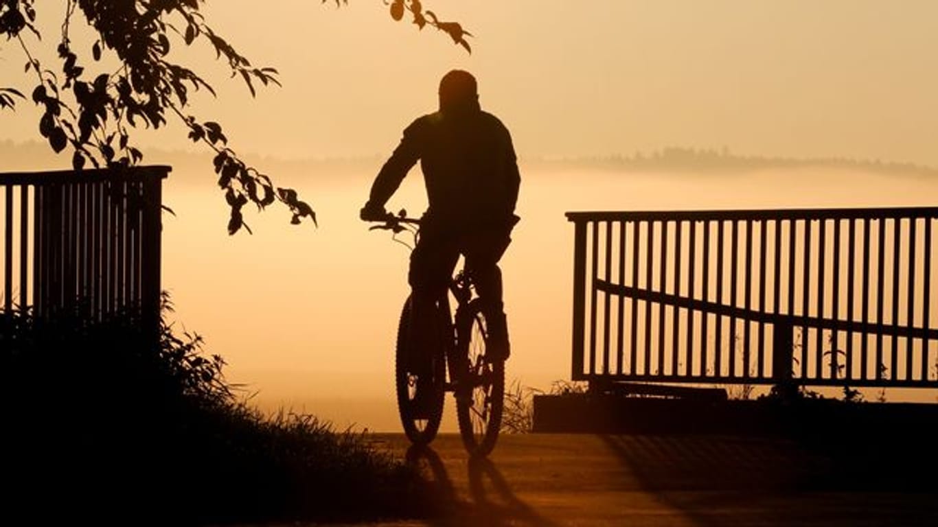 Ein Radfahrer fährt bei Sonnenaufgang über eine Brücke