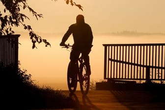 Ein Radfahrer fährt bei Sonnenaufgang über eine Brücke