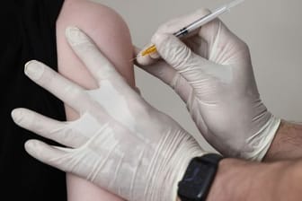 Ein Hausarzt impft einen Jugendlichen in seiner Praxis