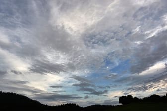 Eine aufgerissene Wolkendecke zieht über ein Wiese hinweg