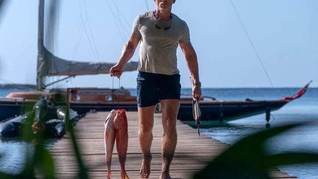 Daniel Craig als James Bond mit Fischen in der Hand in einer Szene des Films "James Bond 007 - Keine Zeit zu sterben".