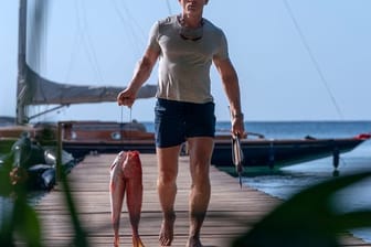 Daniel Craig als James Bond mit Fischen in der Hand in einer Szene des Films "James Bond 007 - Keine Zeit zu sterben".