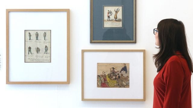 Eine Zeichenserie von Graf von Pocci (1850) schaut sich in der Ausstellung "Unveröffentlicht - Die Comicszene packt aus" eine Fachbesucherin an. Eine Zeichenserie von Graf von Pocci (1850) schaut sich in der Ausstellung "Unveröffentlicht - Die Comicszene packt aus" eine Fachbesucherin an.