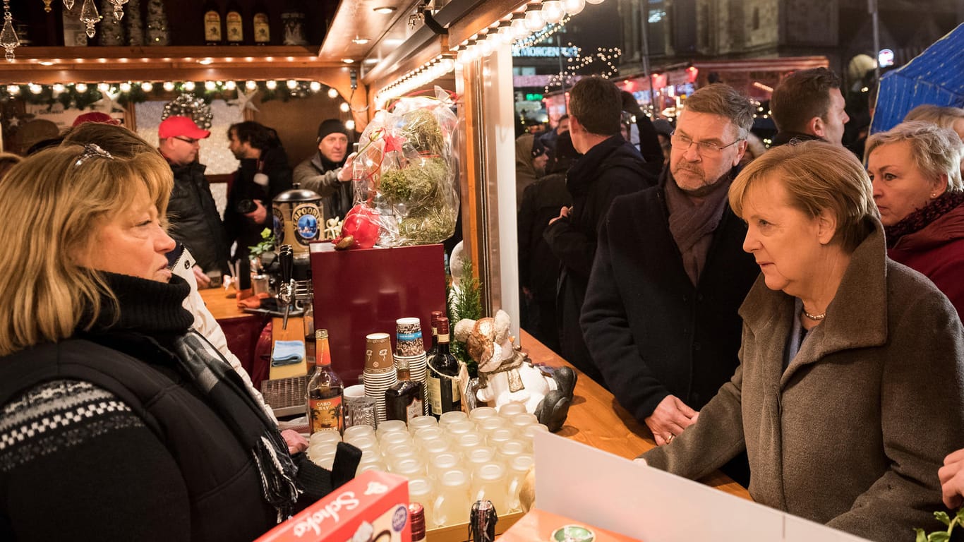 Ein Jahr nach dem Terroranschlag: Bundeskanzlerin Angela Merkel im Gespräch mit Budenbetreibern auf dem Weihnachtsmarkt am Berliner Breitscheidplatz.