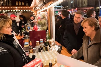 Ein Jahr nach dem Terroranschlag: Bundeskanzlerin Angela Merkel im Gespräch mit Budenbetreibern auf dem Weihnachtsmarkt am Berliner Breitscheidplatz.