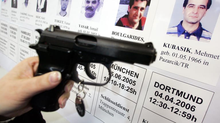 Eine Ceska-Pistole vor einer Bilderwand mit den Porträts der Opfer: Angehörige der Ermordeten litten unter den Ermittlungen der Polizei.